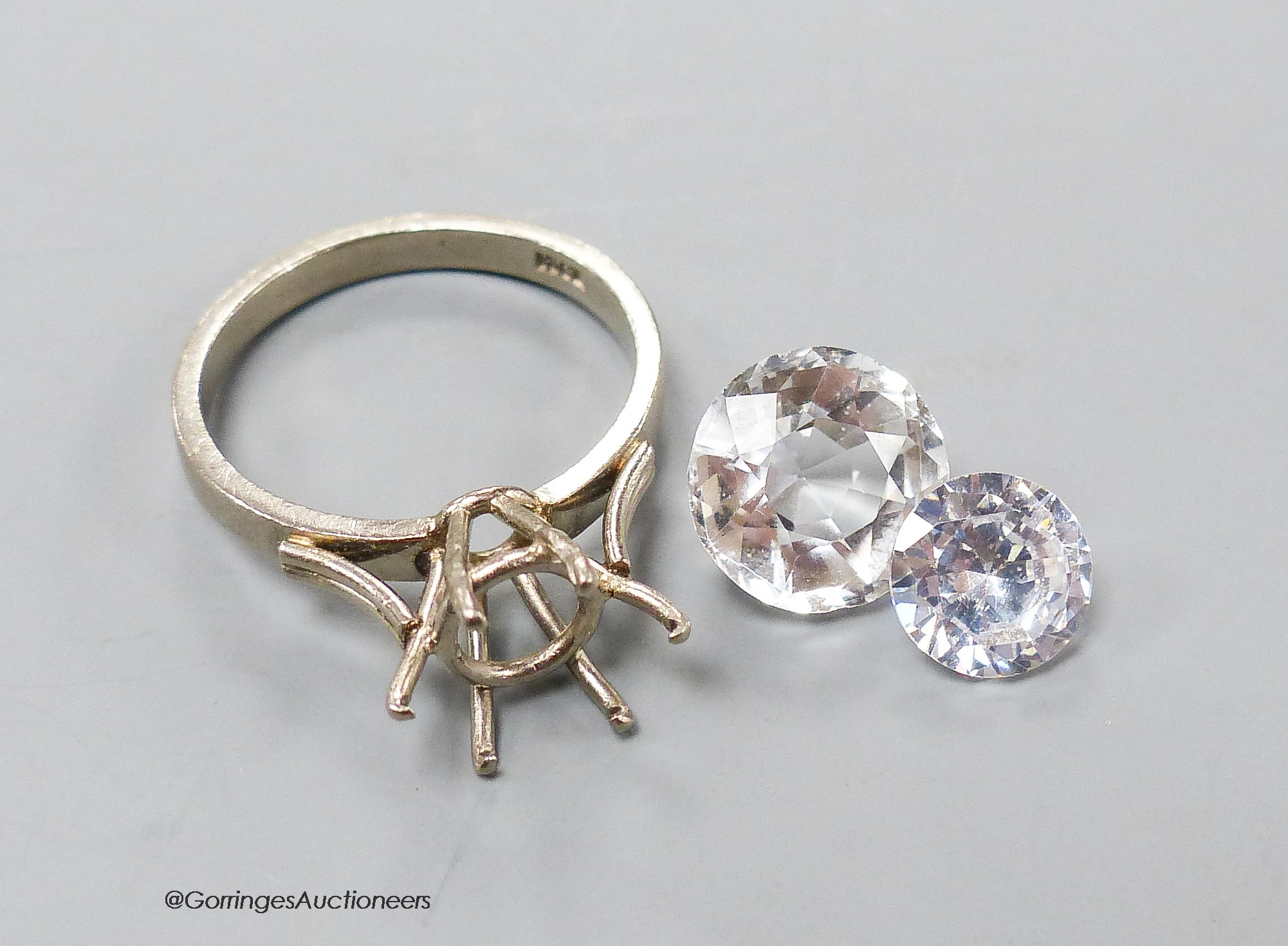 A white metal (stamped 18ct) ring mount, 4.1 grams and two unmounted white paste stones.